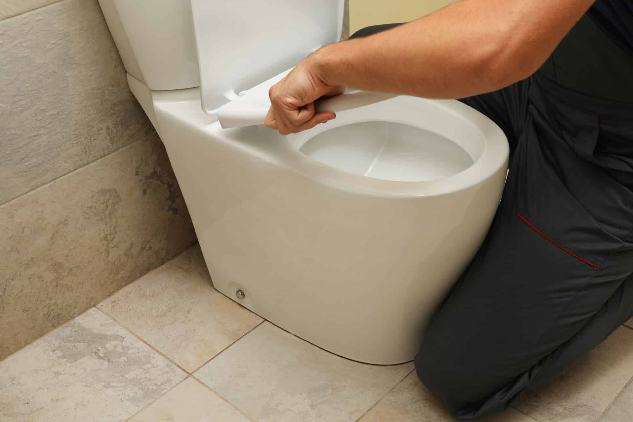 The plumber in overalls fixes the toilet, Toilet Wax Ring.