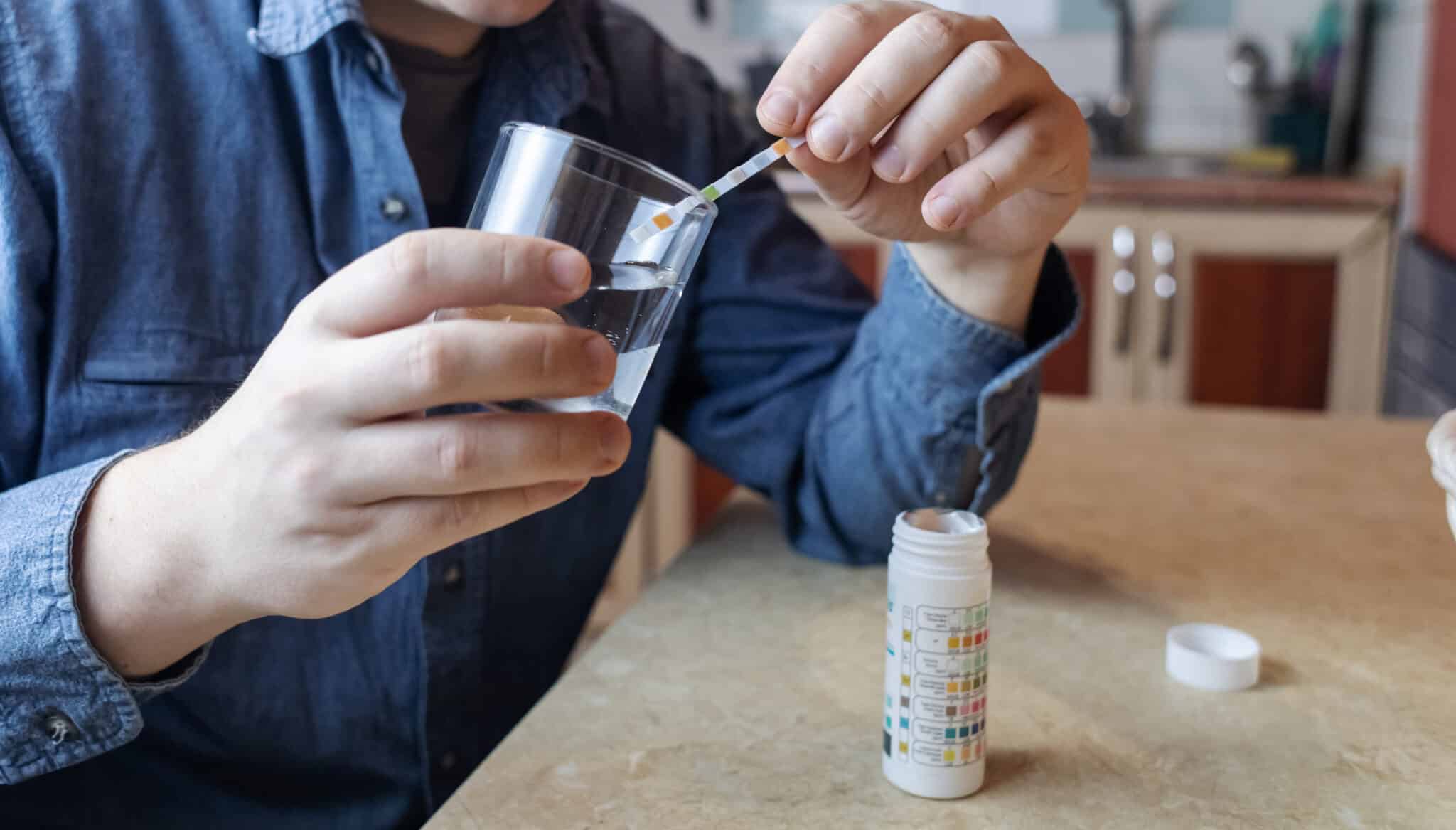Man conducting DIY water quality testing with a home water test kit.